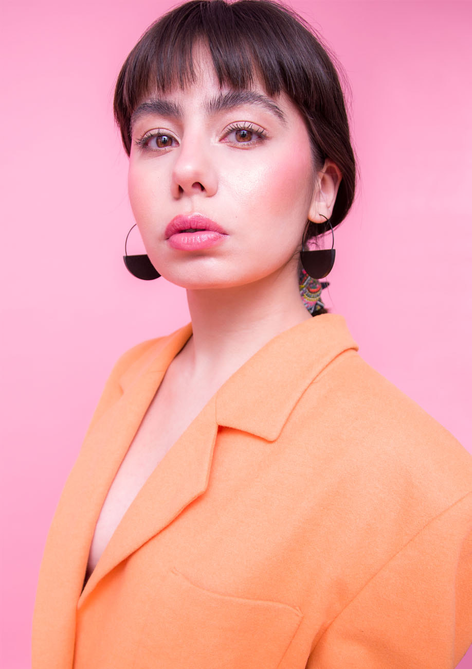 black wooden earrings on model with pink background
