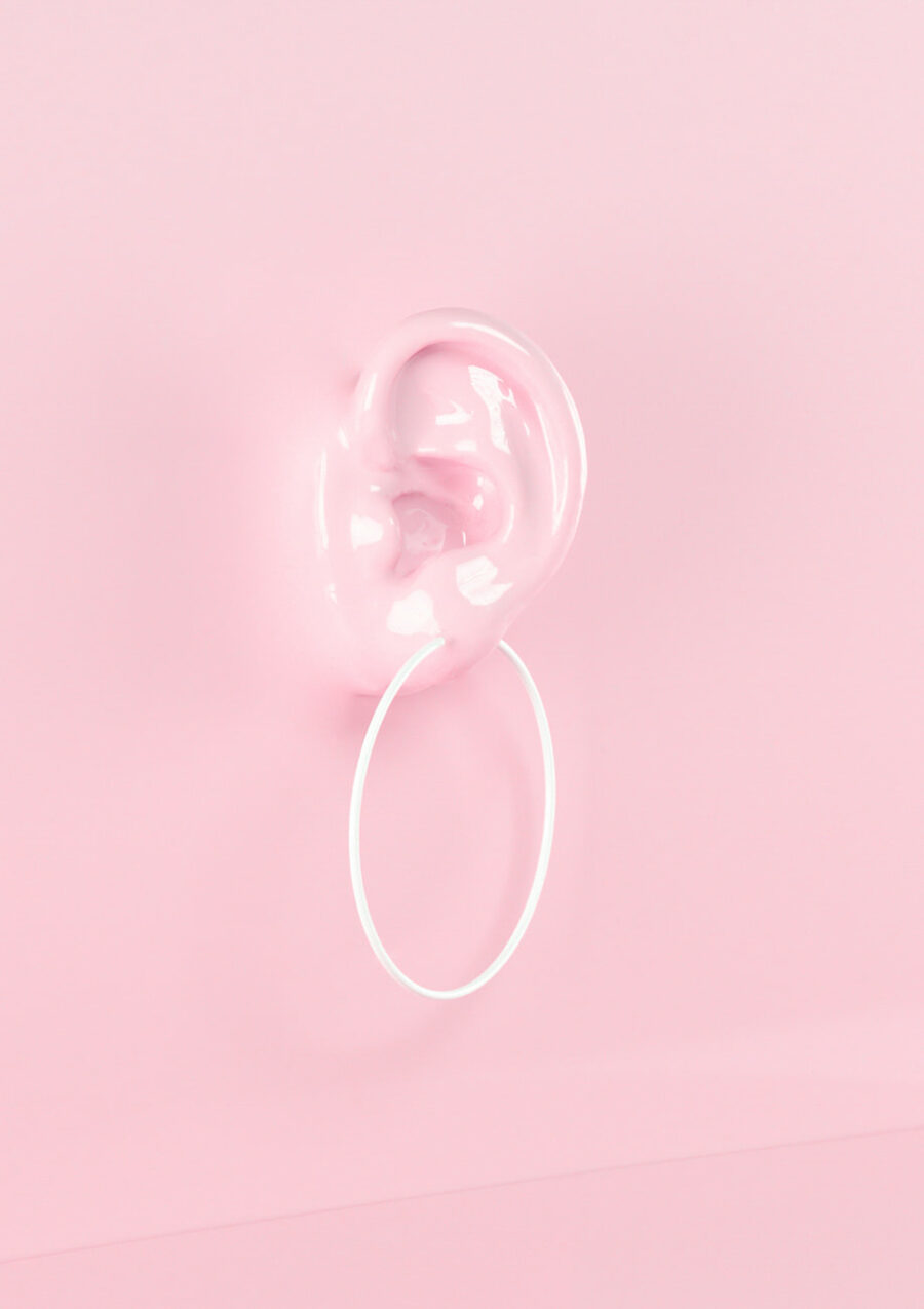 White big hoop earrings on ear with pink background