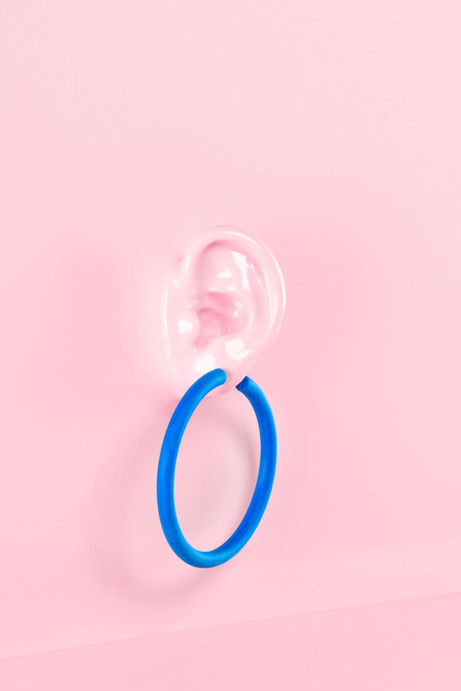 Cobalt blue statement hoop earrings on a pink background.