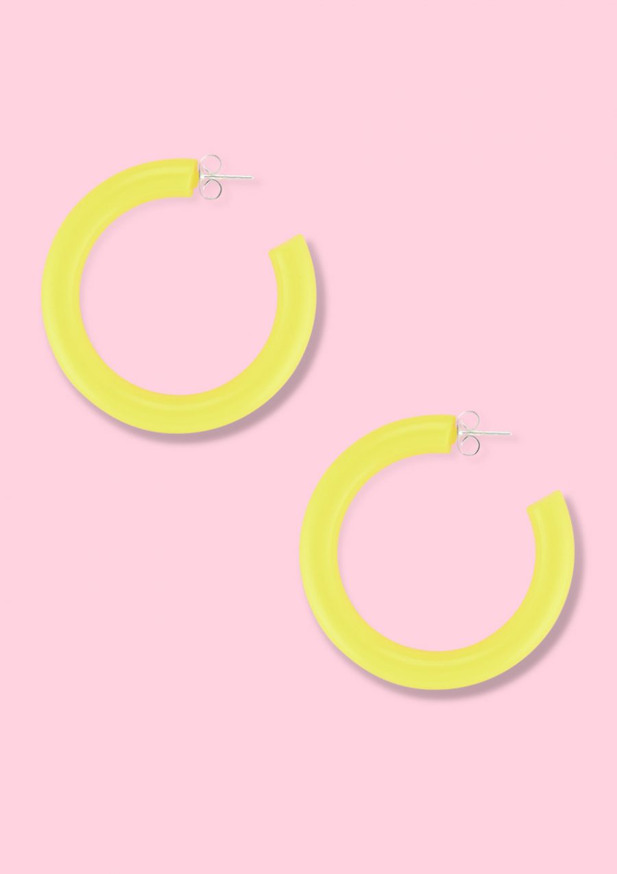 Yellow sustainable vintage hoop earrings on pink background.