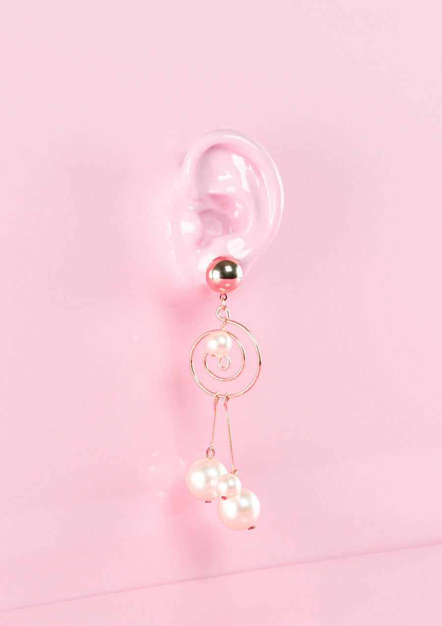 Gold statement drop earrings on pink background